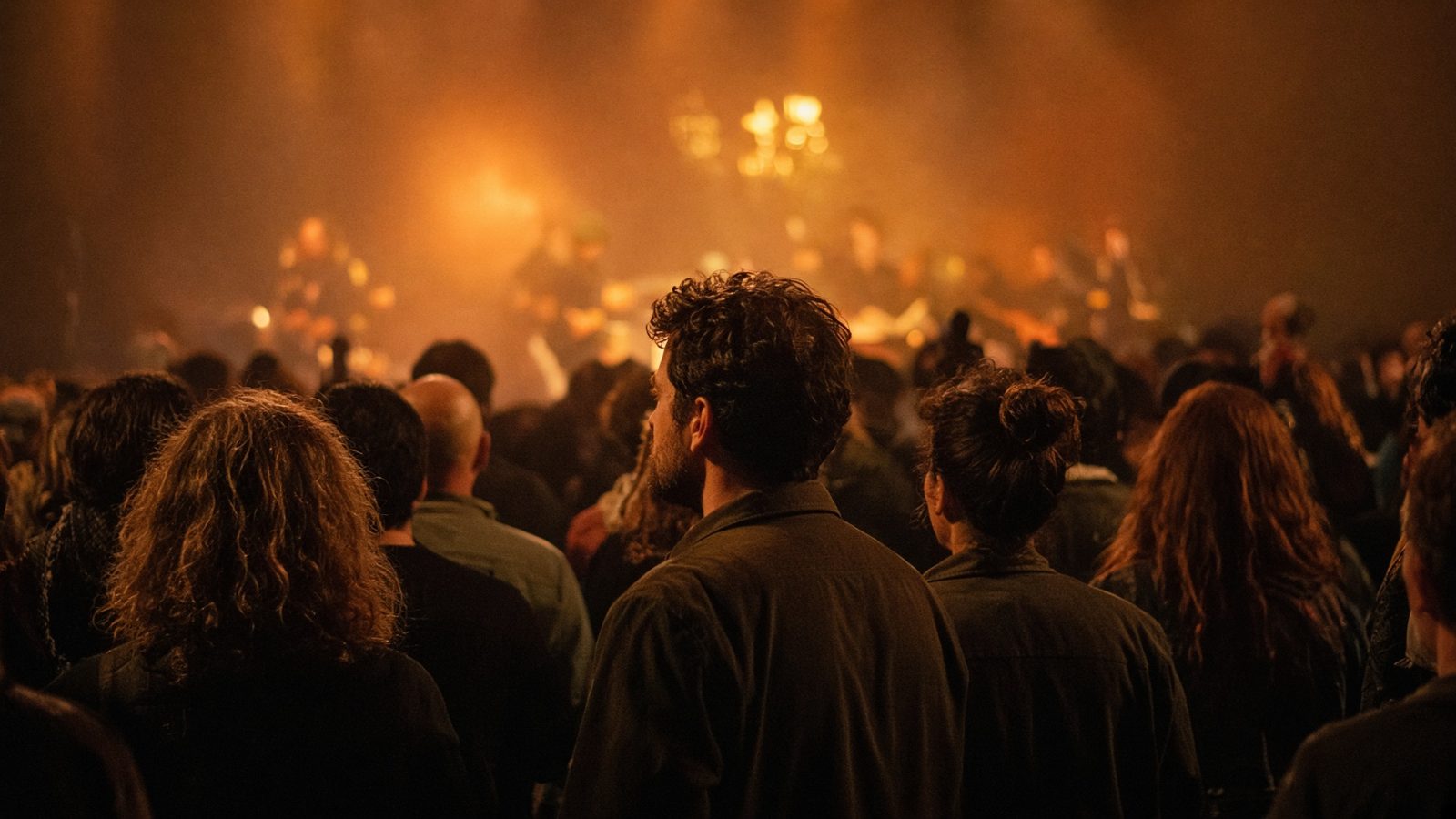 View from a concert crowd toward a warmly lit stage.